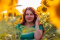 Beautiful young girl with long hair in green summer dress in sunflower field at sunset day Royalty Free Stock Photo