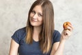 Beautiful young girl with long hair holding a red apple in her hand. Portrait of a beautiful woman with a cute smile. Healthy food Royalty Free Stock Photo