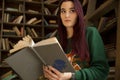 Beautiful young girl with long hair reads a book in the library Royalty Free Stock Photo