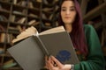 Beautiful young girl with long hair reads a book in the library Royalty Free Stock Photo