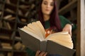 Beautiful young girl with long hair reads a book in the library Royalty Free Stock Photo