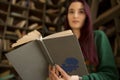 Beautiful young girl with long hair reads a book in the library Royalty Free Stock Photo