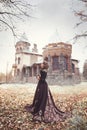 Beautiful young girl in a long vintage dress standing against the background of an old manor.