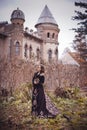 Beautiful young girl in a long vintage dress standing against the background of an old manor.