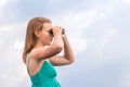 Beautiful young girl looking through binoculars at sea at sunrise in cloudy weather Royalty Free Stock Photo