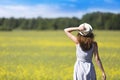 Beautiful young girl looking at a Meadow in a windy day and holding a hat Royalty Free Stock Photo