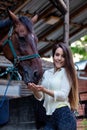 Beautiful young girl looks after her horse in the stable.