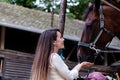 Beautiful young girl looks after her horse in the stable.