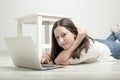 beautiful young girl lying on the floor with a laptop and smiling Royalty Free Stock Photo