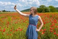 Beautiful young girl making selfie with mobile phone in a poppy