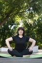 Beautiful young girl meditates in the park sitting on a green yoga mat with hands on legs. Healthy lifestyle. Lotus position Royalty Free Stock Photo