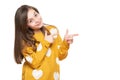 Beautiful young girl in mustard yellow sweater looking at camera, smiling and pointing to the side. Waist up studio shot. Royalty Free Stock Photo