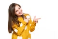 Beautiful young girl in mustard yellow sweater looking at camera, smiling and pointing to the side. Waist up studio shot on white. Royalty Free Stock Photo