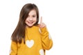 Beautiful young girl in mustard yellow sweater looking at camera, smiling and pointing up. Waist up studio shot white background. Royalty Free Stock Photo