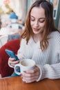 Beautiful young girl in outdoor uses smart phone and texting Royalty Free Stock Photo