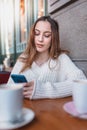 Beautiful young girl in outdoor uses smart phone and texting Royalty Free Stock Photo