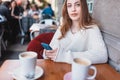 Beautiful young girl in outdoor uses smart phone and texting Royalty Free Stock Photo