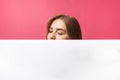 Beautiful young girl peeking out from behind white paper wall, on rose background Royalty Free Stock Photo