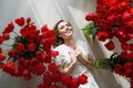 A beautiful young girl in a peignoir is lying on the floor between large bouquets of tulips. March 8 concept.