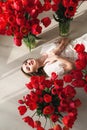 A beautiful young girl in a peignoir is lying on the floor between large bouquets of tulips. March 8 concept.