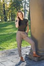 Beautiful young girl is phoning standing in autumn park