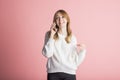 Beautiful young girl on a pink background in the studio speaks by phone. Royalty Free Stock Photo