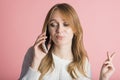Beautiful young girl on a pink background in the studio speaks by phone. Royalty Free Stock Photo