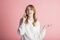 Beautiful young girl on a pink background in the studio speaks by phone. Royalty Free Stock Photo