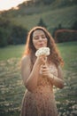 Beautiful young girl playing in dandelion field in beautiful spring warm sunset Royalty Free Stock Photo