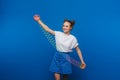 Beautiful young girl playing with a rainbow slinky, a toy of her childhood on a blue background