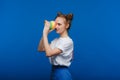 Beautiful young girl playing with a rainbow slinky, a toy of her childhood on a blue background