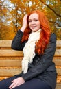 Beautiful young girl portrait sit on bench in park, yellow leaves at fall season, redhead, long hair Royalty Free Stock Photo