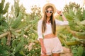 Young girl in hat and sunglasses posing against cactuses Royalty Free Stock Photo