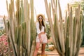 Young girl in hat and sunglasses posing against cactuses Royalty Free Stock Photo