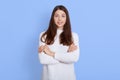 Beautiful young girl posing with folded arms and looking directly at camera, looks happy, expressing confidence, standing isolated Royalty Free Stock Photo