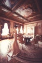 A beautiful young girl in a powdery wedding dress on the background of the interiors of a luxurious historical apartment.