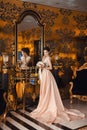 A beautiful young girl in a powdery wedding dress on the background of the interiors of a luxurious historical apartment. Royalty Free Stock Photo