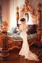 A beautiful young girl in a powdery wedding dress on the background of the interiors of a luxurious historical apartment.