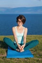 Beautiful young girl practicing yoga on the lake