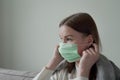 Beautiful young girl puts on a green medical mask on her face. Orvi, coronovirus, acute respiratory infections.