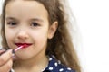 Beautiful young girl putting on red lipstick. Royalty Free Stock Photo