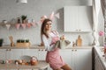 A beautiful young girl in rabbit ears holds an Easter cake in her hands standing near the table in the home kitchen. Royalty Free Stock Photo