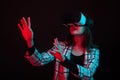 Beautiful young girl reaching out with her hands and wearing virtual reality goggles in studio with color gels lighting Royalty Free Stock Photo