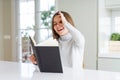 Beautiful young girl reading a book at home with happy face smiling doing ok sign with hand on eye looking through fingers Royalty Free Stock Photo