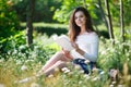 Beautiful young girl reads a book in park outdoors Royalty Free Stock Photo