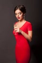 Beautiful young girl in red dress standing with glass of champagne Royalty Free Stock Photo