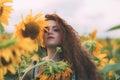 Beautiful young girl with red wavy hair and freckles in stripped colourful dress enjoying nature on the field of sunflowers. Royalty Free Stock Photo