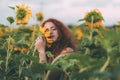 Beautiful young girl with red wavy hair and freckles in stripped colourful dress enjoying nature on the field of sunflowers. Royalty Free Stock Photo