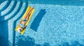 Beautiful young girl relaxing in swimming pool, swims on inflatable mattress and has fun in water on family vacation, aerial view Royalty Free Stock Photo