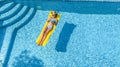 Beautiful young girl relaxing in swimming pool, swims on inflatable mattress and has fun in water on family vacation, aerial view Royalty Free Stock Photo